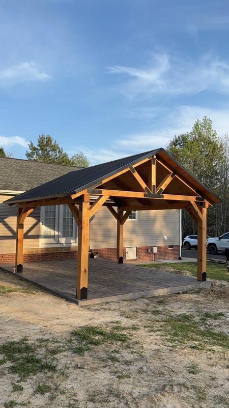 Stained pavilion with black metal roof attached to home